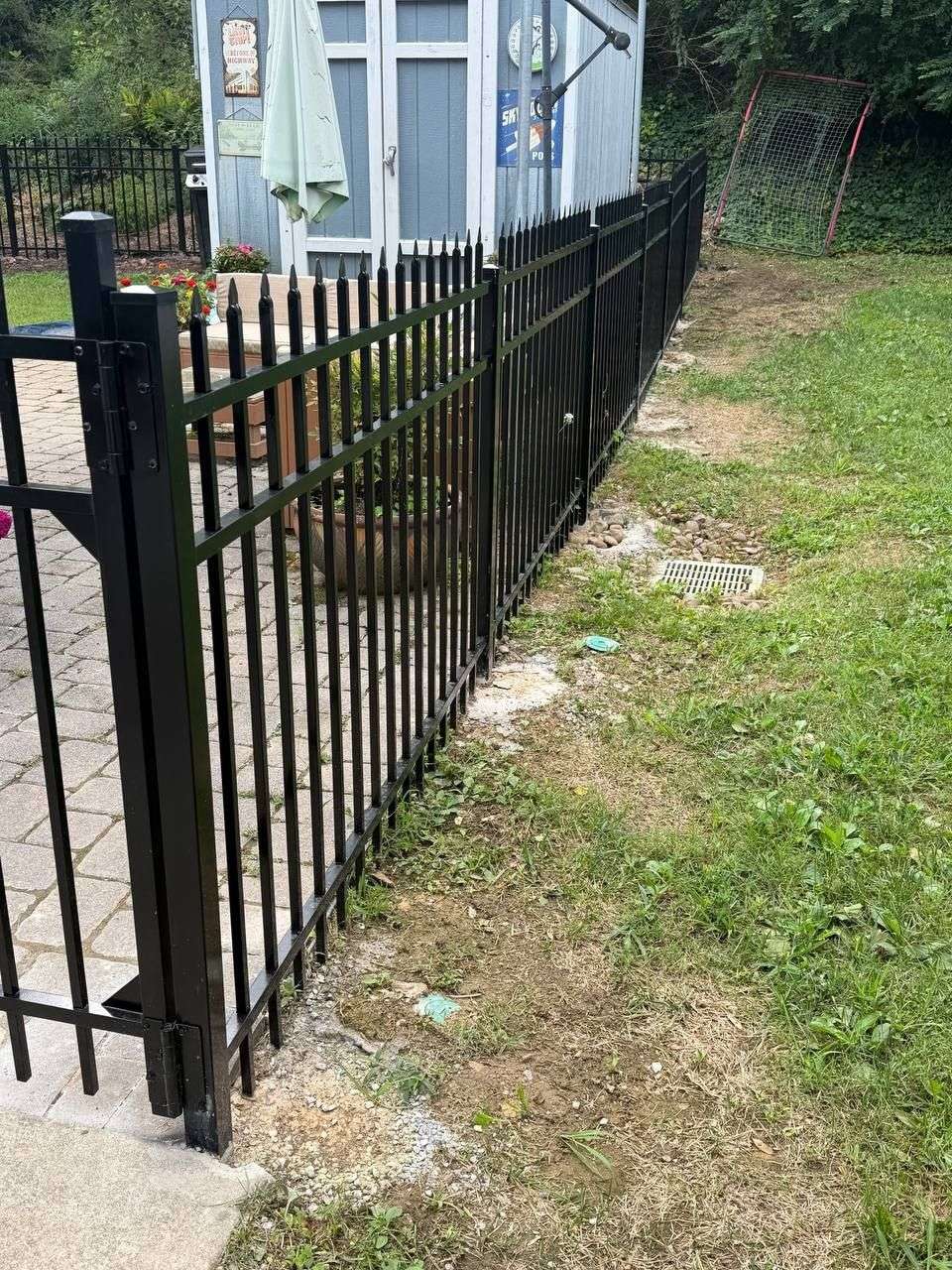 Black aluminum ornamental fence and matching gate set in concrete along a graded yard in Chattanooga