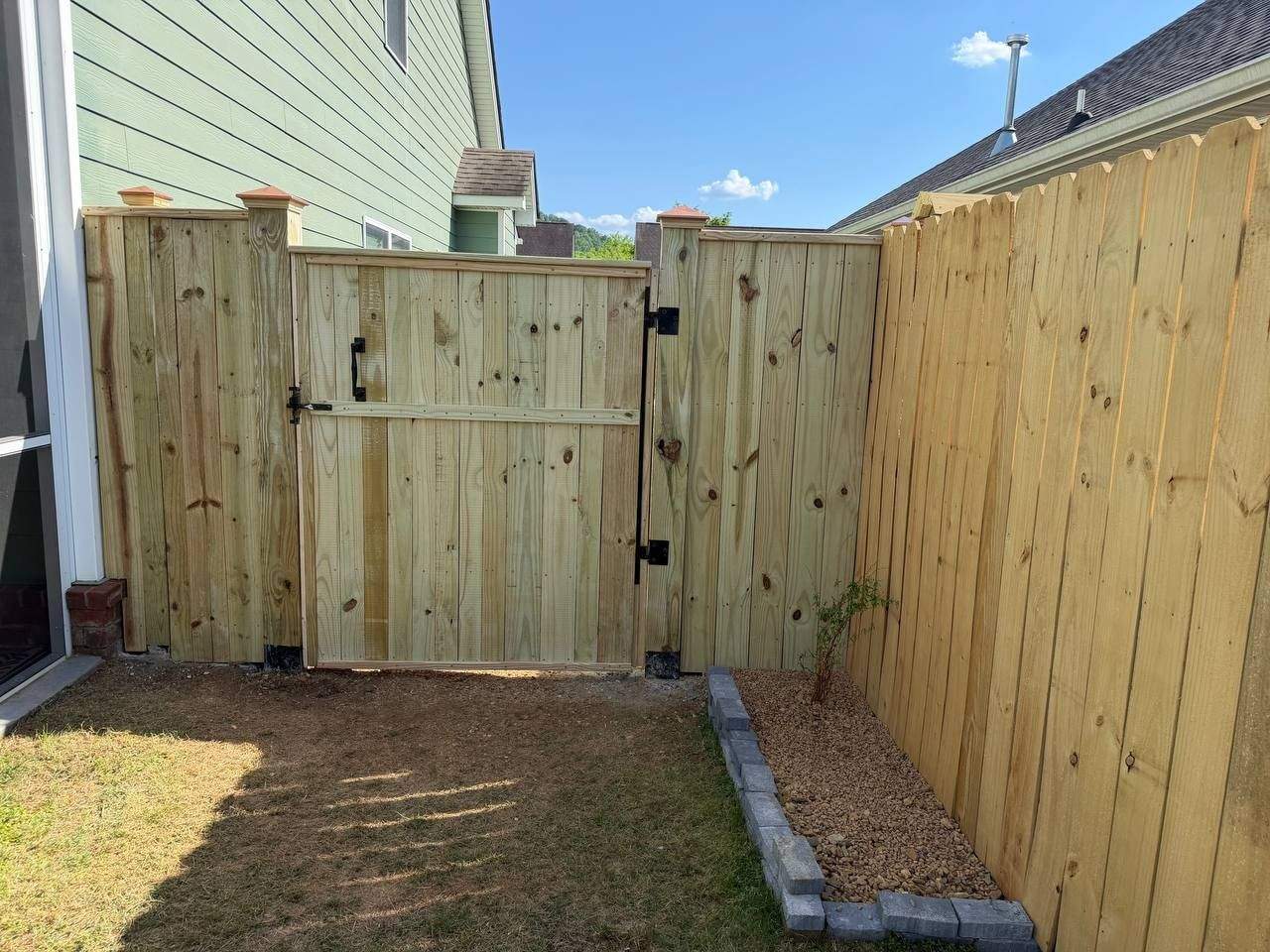 Custom-built wood swing gate with black hardware set into a capped wood privacy fence in Chattanooga